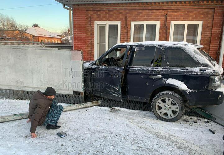 Проломил забор: в Краснодаре на улице Гастелло на скользкой дороге не удержался кроссовер